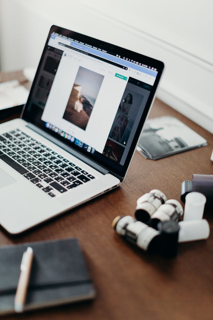 Close-up of a laptop on a desk with film rolls, showcasing photography workflow.